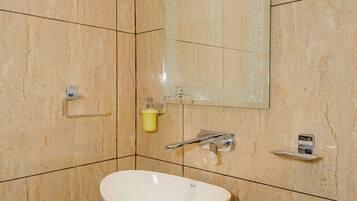 A bathroom with a white sink, a mirror, and a yellow soap dispenser.