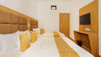 A hotel room with two beds, a wooden headboard, a desk with a TV, and a ceiling fan.