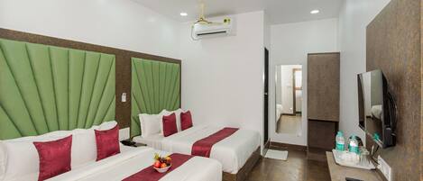 A hotel room with two beds, a TV, and an air conditioning unit.