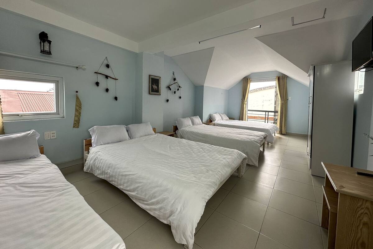 A bedroom with three beds, a window, and a refrigerator.