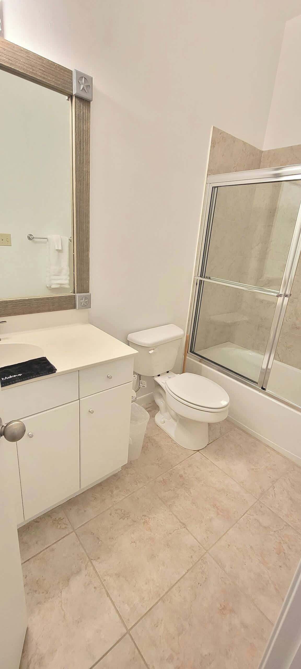 Une salle de bain avec un meuble-lavabo blanc, des toilettes et une douche à parois de verre.