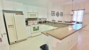 A kitchen with white cabinets, a granite countertop, a microwave, and a sink. - Pool - Beach Access - Near Claytons Private (South Padre Island)