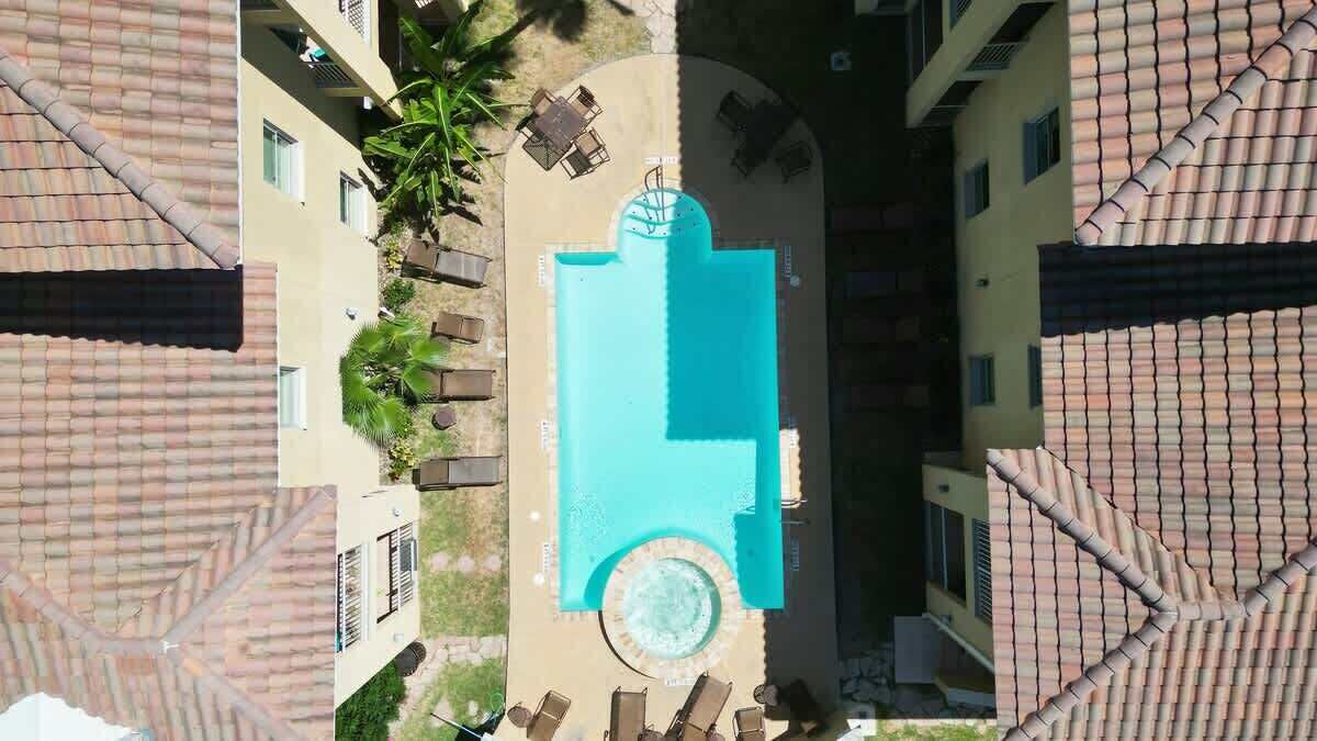 A rooftop pool with a circular hot tub, surrounded by lounge chairs and a small table.