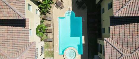 A rooftop pool with a circular hot tub, surrounded by lounge chairs and a small table.