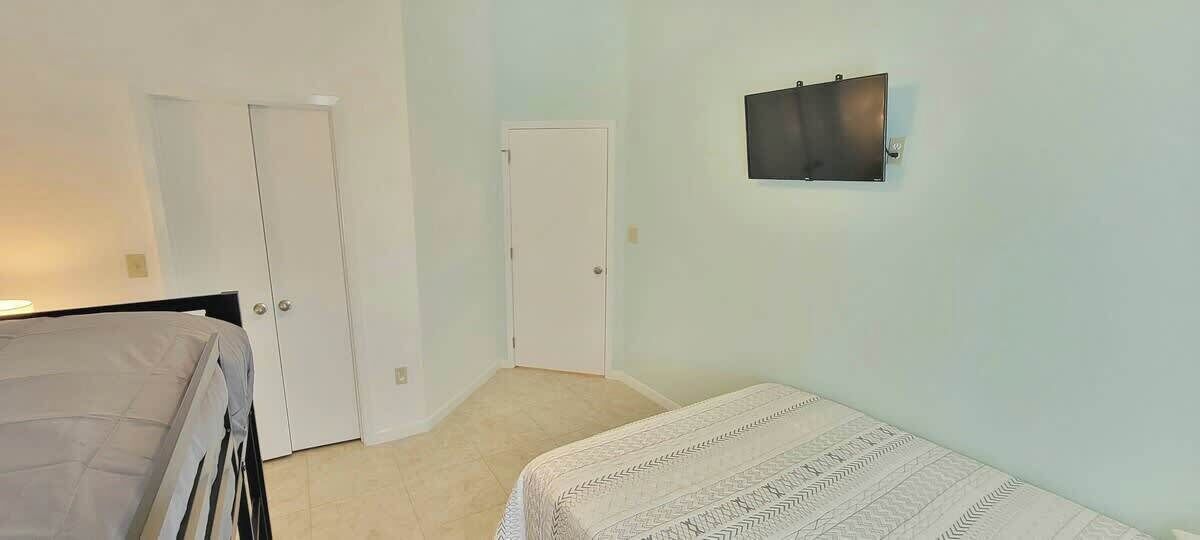 A bedroom with a bed, a desk, and two doors.