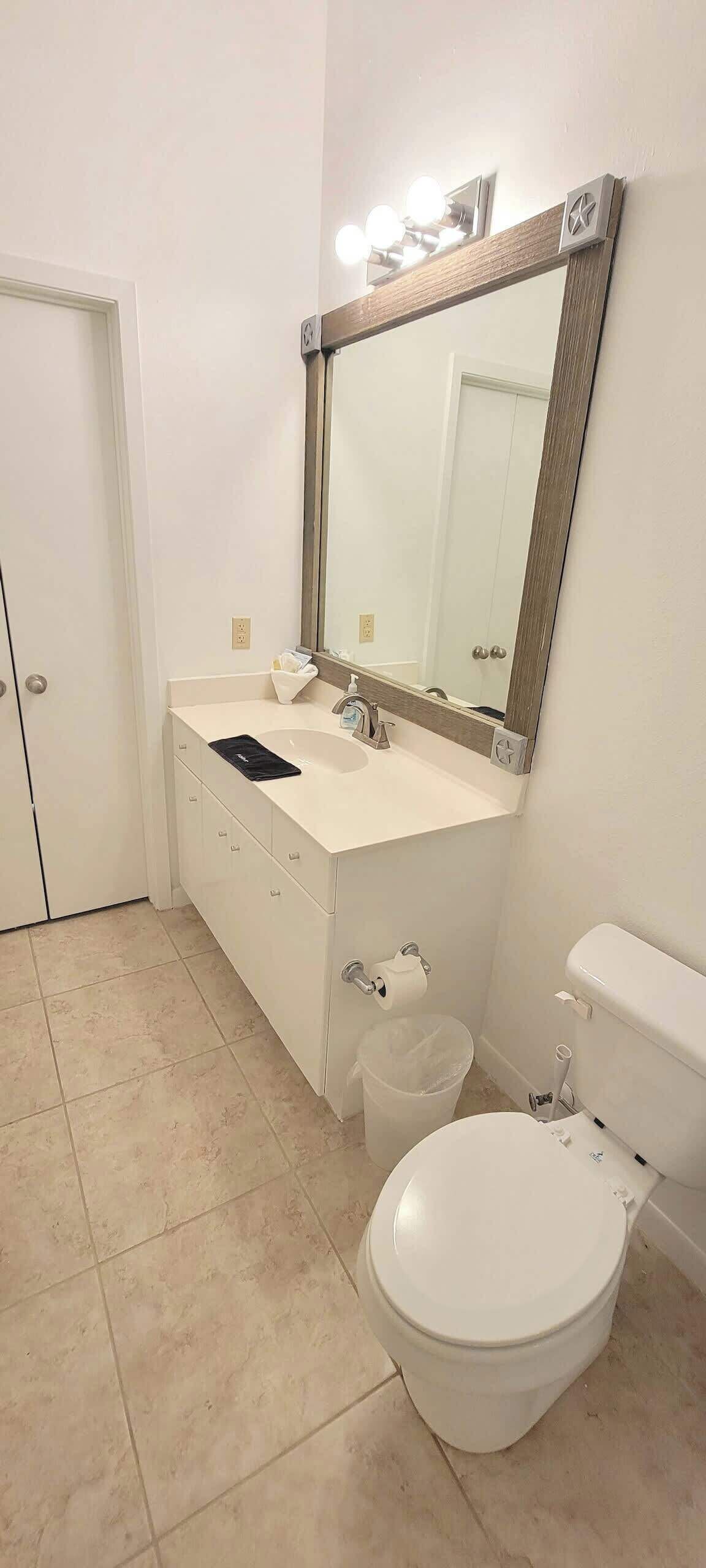 Une salle de bain avec un lavabo blanc, un miroir et des toilettes.