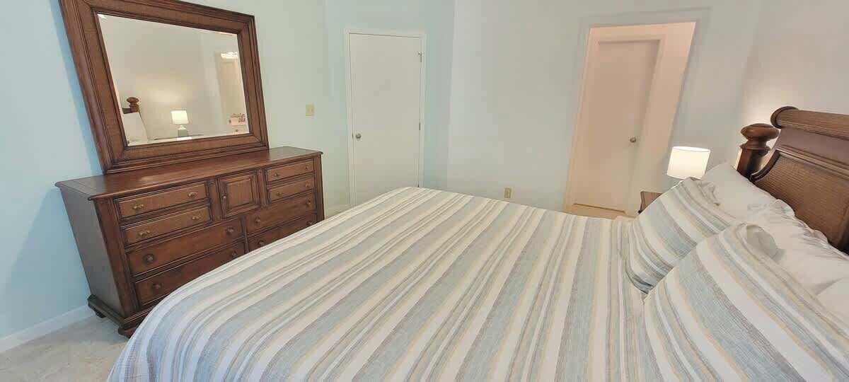 Un dormitorio con cama, cómoda, espejo y dos puertas.