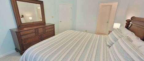 Un dormitorio con cama, cómoda, espejo y dos puertas.