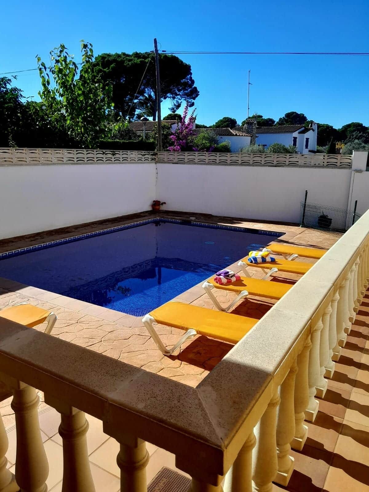 A swimming pool with yellow lounge chairs and a white balustrade.