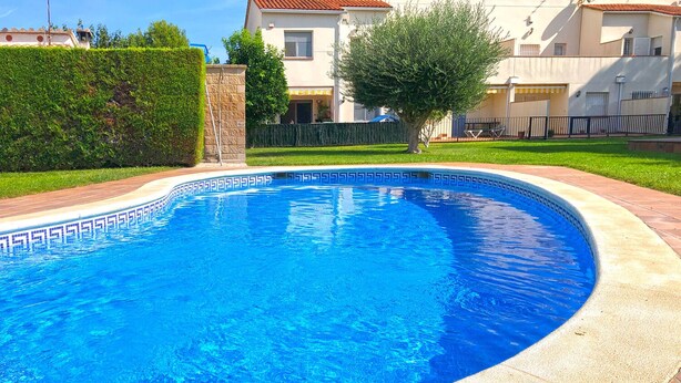 A swimming pool with a decorative edge, surrounded by a paved deck and a well-maintained lawn. - Villa with shared Pool/Aircon/Wi-Fi - Villa Mimosa (L'Escala)
