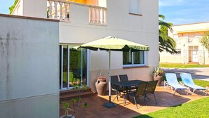 A patio with a table and chairs, a green umbrella, and potted plants. - Villa with shared Pool/Aircon/Wi-Fi - Villa Mimosa (L'Escala)