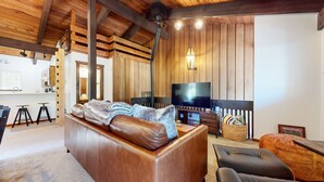 A cozy living room with a leather sofa, a television, and a wooden ceiling. - Private Lodge, Vaulted Ceilings, Gas Grill, Washer/Dryer, Walk to The Village (Mammoth Lakes)