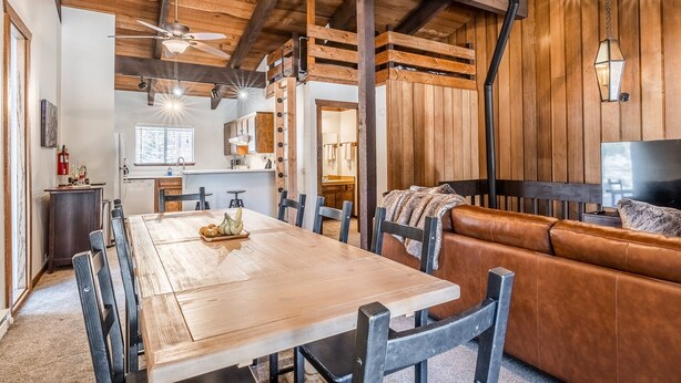 A spacious living area with a wooden ceiling, a dining table with chairs, a leather sofa, and a television. - Private Lodge, Vaulted Ceilings, Gas Grill, Washer/Dryer, Walk to The Village (Mammoth Lakes)