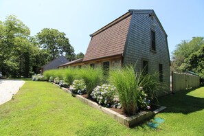 Une maison de plain-pied, dotée d’un toit en pente, entourée d’une pelouse bien entretenue et de parterres de fleurs.