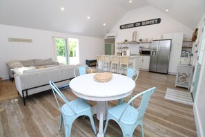 Une cuisine moderne avec un réfrigérateur en acier inoxydable, un coin repas avec une table ronde et des chaises, et une enseigne indiquant « SEASIDE ON SURREY ».
