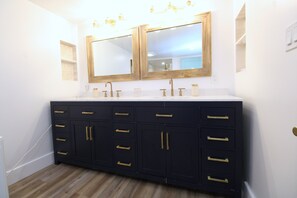 Un bagno con doppio lavabo, due vasche e uno specchio grande.
