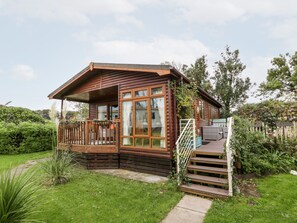 A wooden cabin with a porch, a staircase, and a garden. - Eden Lodge (Newton Stewart)