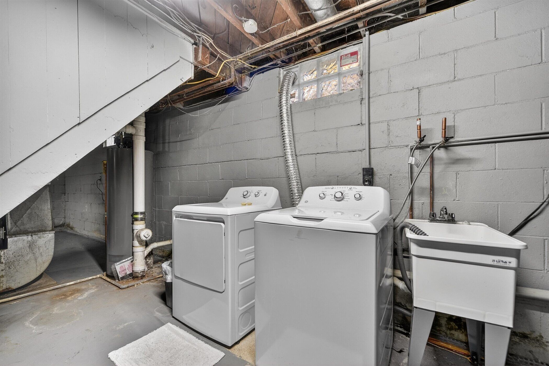 A laundry area with two front-loading washing machines and a sink.