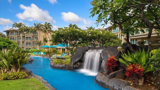 Ein Hotel mit Swimmingpool, Wasserfall und üppiger Vegetation.