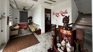 A spacious living room with a high ceiling, a staircase, and a wall with a decorative inscription. - OYO 1204 Hoang Linh Hotel (Xuan Huong - Da Lat)