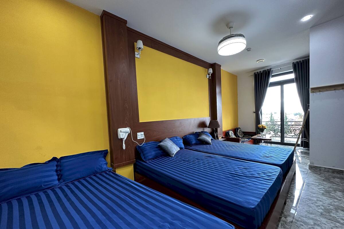 A hotel room with two beds, a desk, a chair, and a window with curtains.