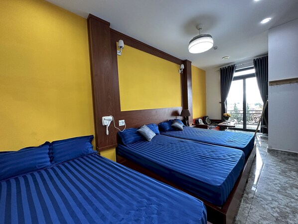 Una camera d'albergo con due letti, una scrivania, una sedia e una finestra con tende.