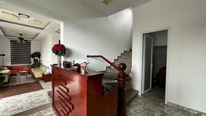 A spacious living area with a red reception desk, a staircase, and a large window with blinds. - OYO 1204 Hoang Linh Hotel (Xuan Huong - Da Lat)