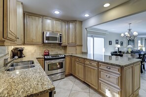 Eine Küche mit Granit-Arbeitsplatten, Edelstahlgeräten, Holzausbau und einer großen Insel mit Spüle.