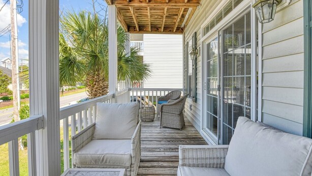A covered porch with wicker furniture and a view of the street. - Spacious 4 Bedroom, 3.5 Bath Garden City Beach Home with Private Pool (Garden City Beach)