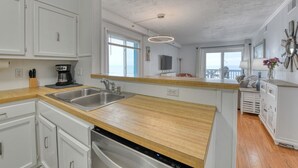 A modern kitchen with white cabinets, stainless steel appliances, and a wooden countertop. - Beach House 217, two-bedroom, two-bath ocean front condo (Garden City Beach)