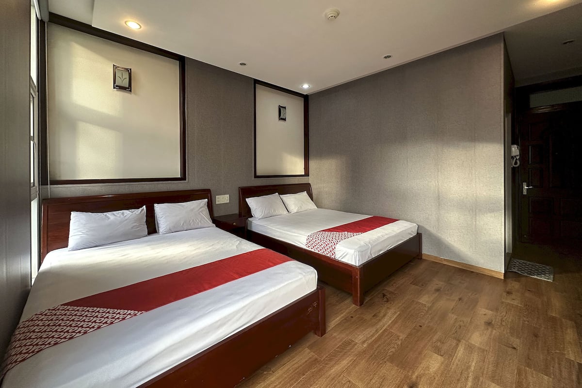 A hotel room with two beds, wooden flooring, and recessed ceiling lights.