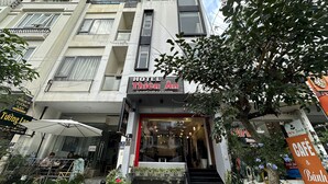 Hotel com fachada moderna, várias varandas e entrada visível com degraus até a porta.