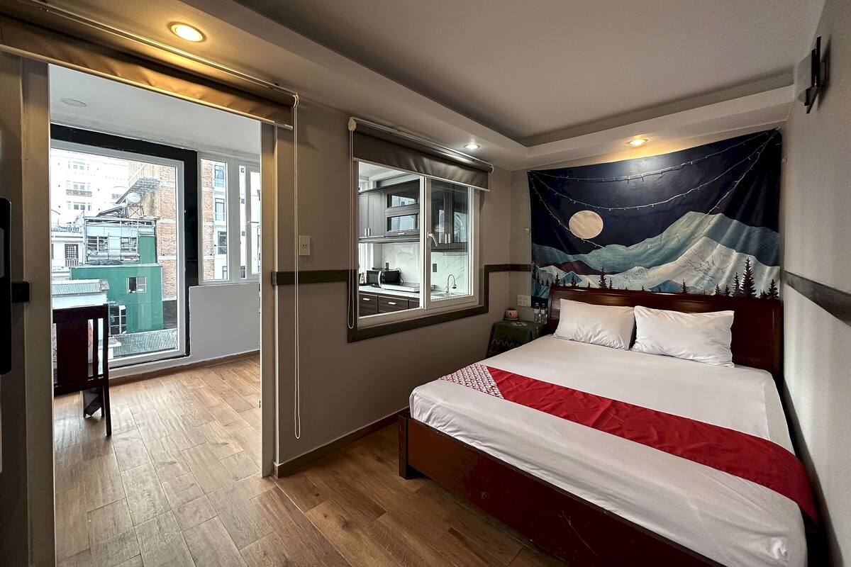 A hotel room with a bed, a large mirror, a night sky tapestry, and a view of the city through a sliding door.