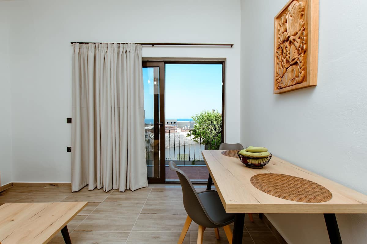 A modern room with a wooden table, black chairs, a view through a glass door, and a wooden carving on the wall.