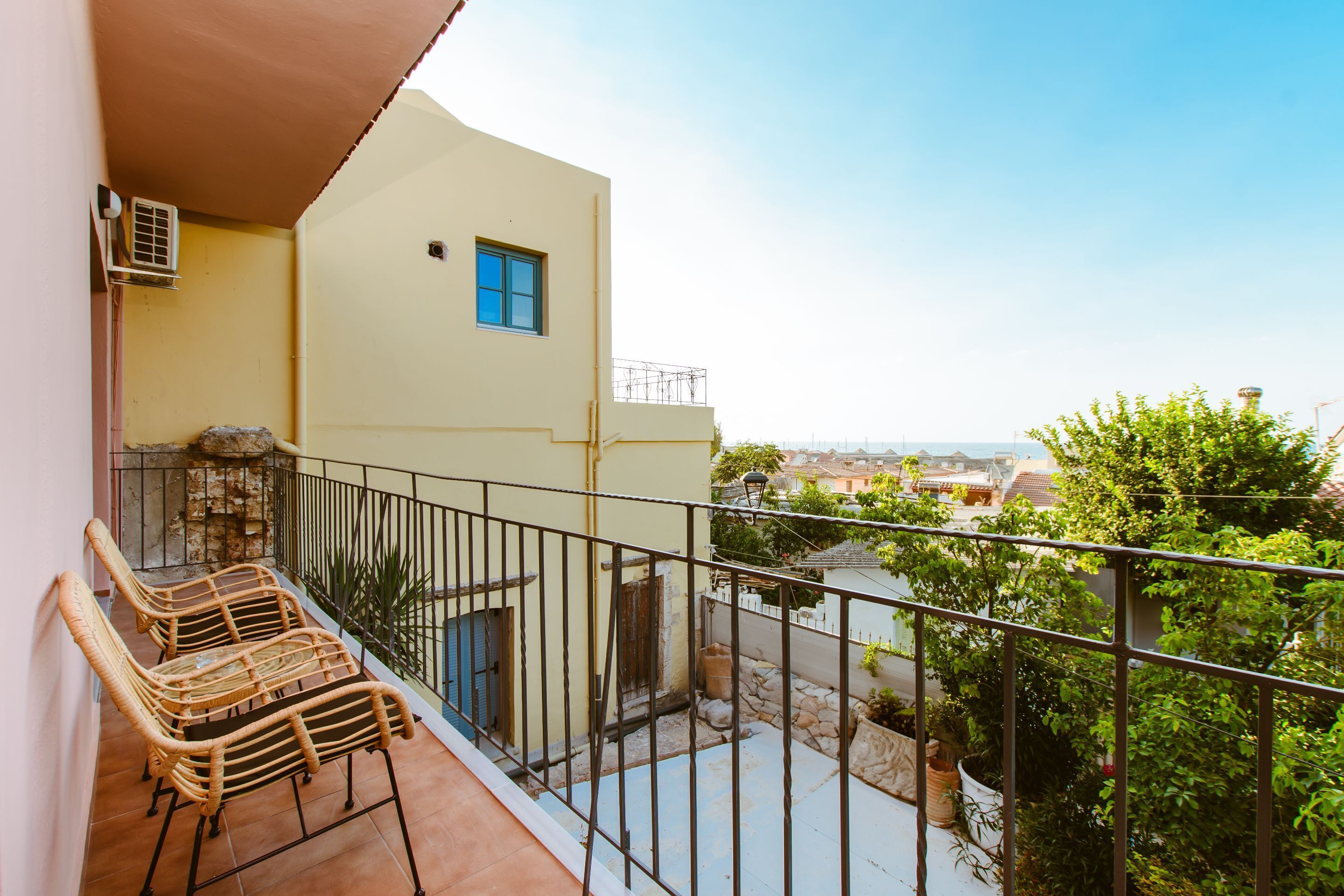 Un balcone con sedie in vimini, un piccolo muro in pietra e vista sulla città.