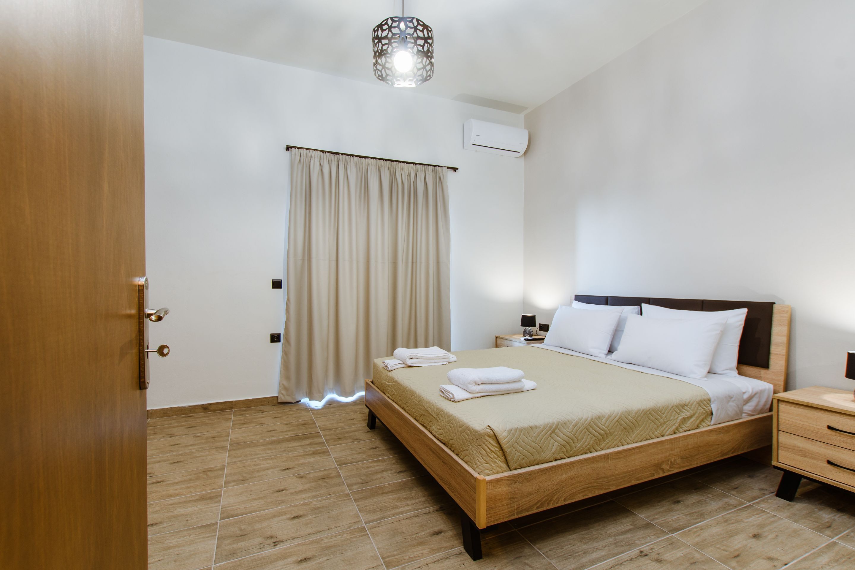 Ein Schlafzimmer mit einem hölzernen Bett, einem Nachttisch, einer Lampe und einer Deckenleuchte.