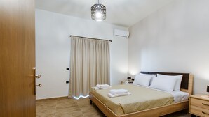 A bedroom with a wooden bed, a nightstand, a lamp, and a ceiling light fixture. - Krinis houses next the old harbour (Chania)