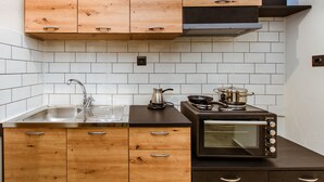 A kitchen with wooden cabinets, a stainless steel sink, a black countertop, and a built-in oven. - Krinis houses next the old harbour (Chania)