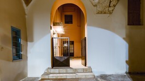 An arched doorway leading to a room with a tiled floor and a small window. - Krinis houses next the old harbour (Chania)