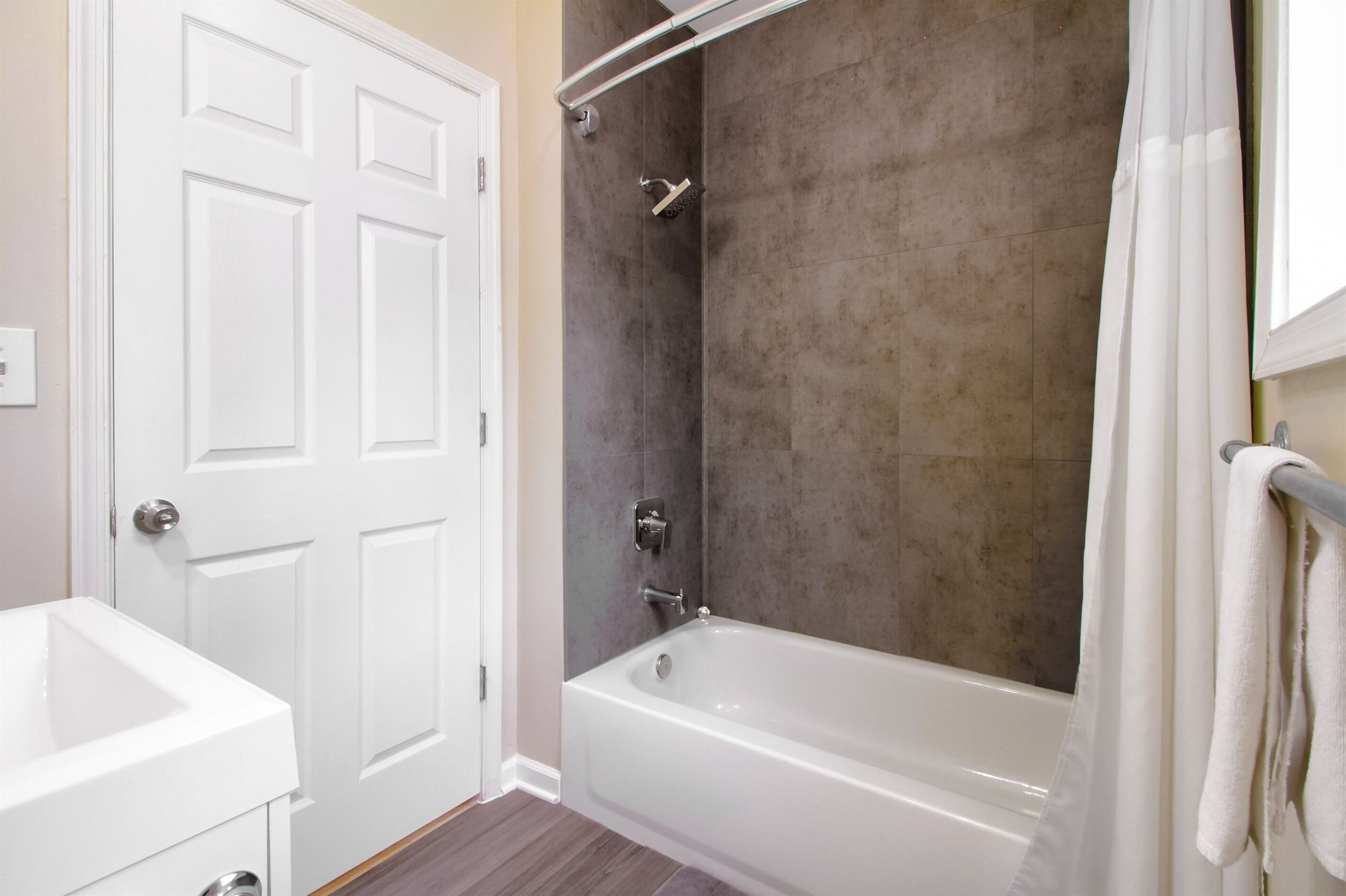 A bathroom with a white bathtub, a shower, and a white sink.