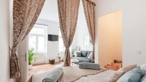A bedroom with a bed, curtains, a TV, and a sofa in the background. - Luxurious and Bright, 5 min walk to city center (Vienna)
