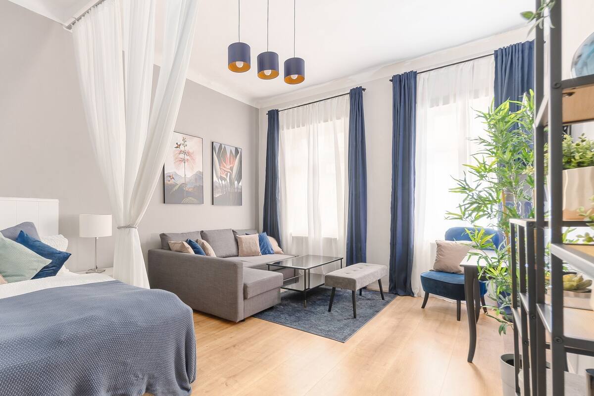 A modern hotel room with a bed, a sofa, a coffee table, and a desk.