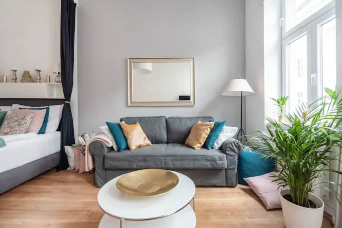 A modern living room with a grey sofa, a white coffee table, and a large mirror on the wall.