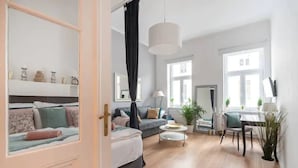 A modern living room with a sofa, a coffee table, and a dining area with a table and chairs. - Luxurious and Bright, 5 min walk to city center (Vienna)
