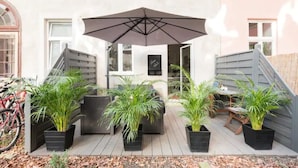 An outdoor patio area with a large umbrella, seating, and potted plants. - Luxurious and Bright, 5 min walk to city center (Vienna)