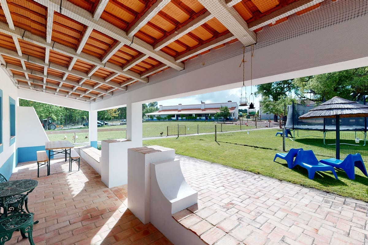 A covered patio area with outdoor seating, a view of a grassy field, and a playground in the background.