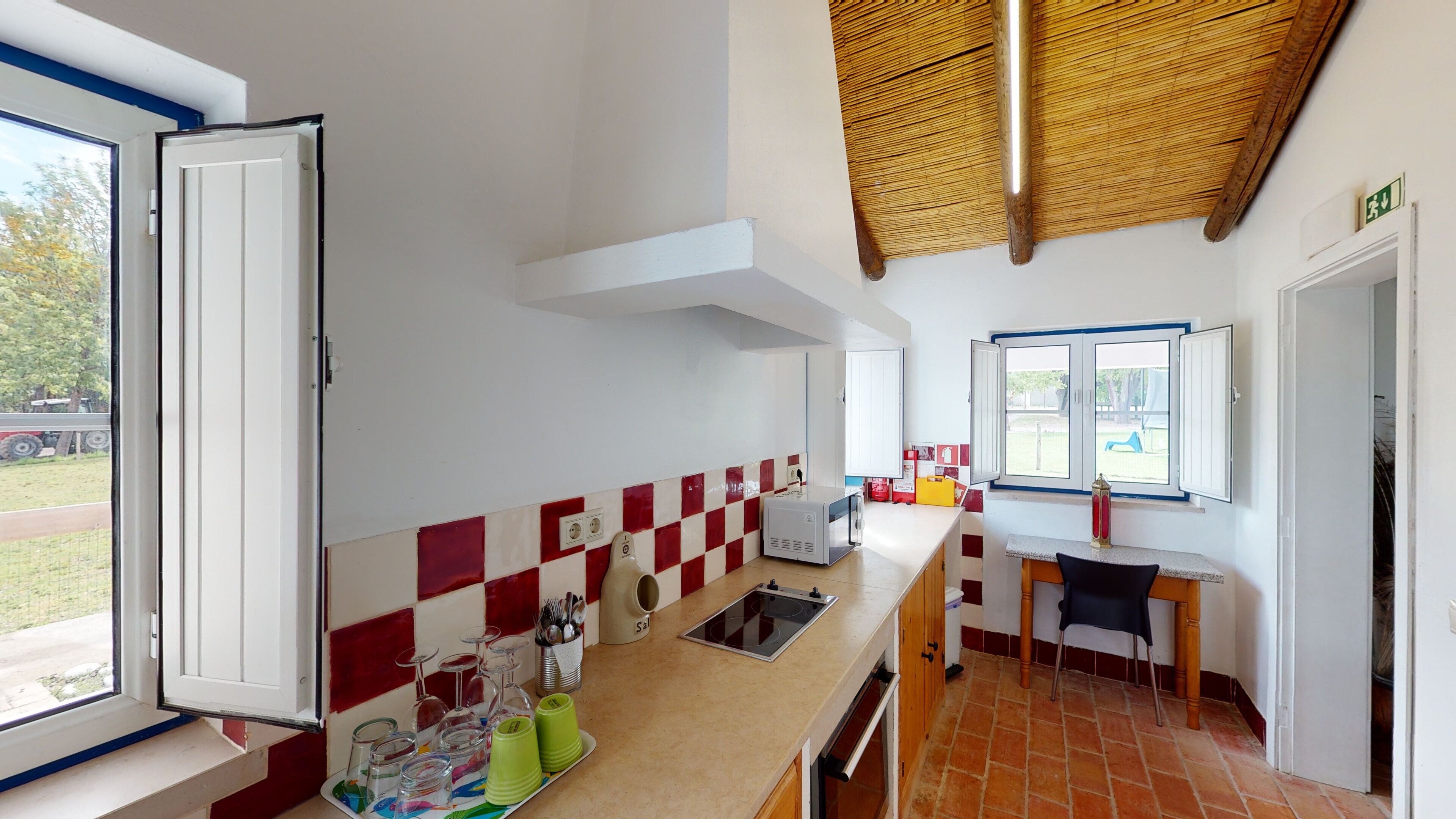 Una cocina con salpicadero a cuadros, estufa y ventana con vista a un jardín.