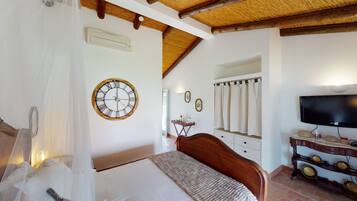 Un dormitorio con cama, techo de madera, televisor montado en la pared, mesita de noche y espejo.
