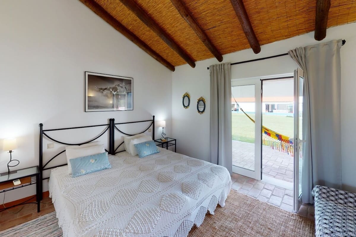 A bedroom with a bed, bedside tables, a window, and a view of a playground.