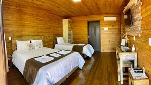 Una habitación tipo cabaña de madera con dos camas, una mesita y un estante.